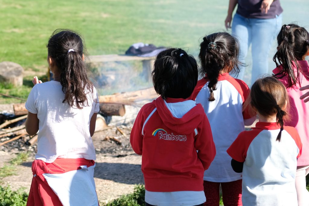 A back view of Rainbows watching a campfire
