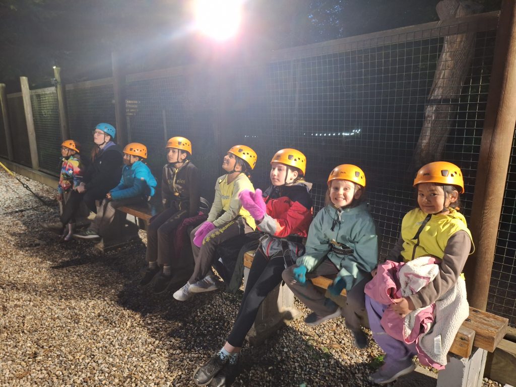 A row of Brownies sitting in their yellow helmets with a leader in their blue helmet.