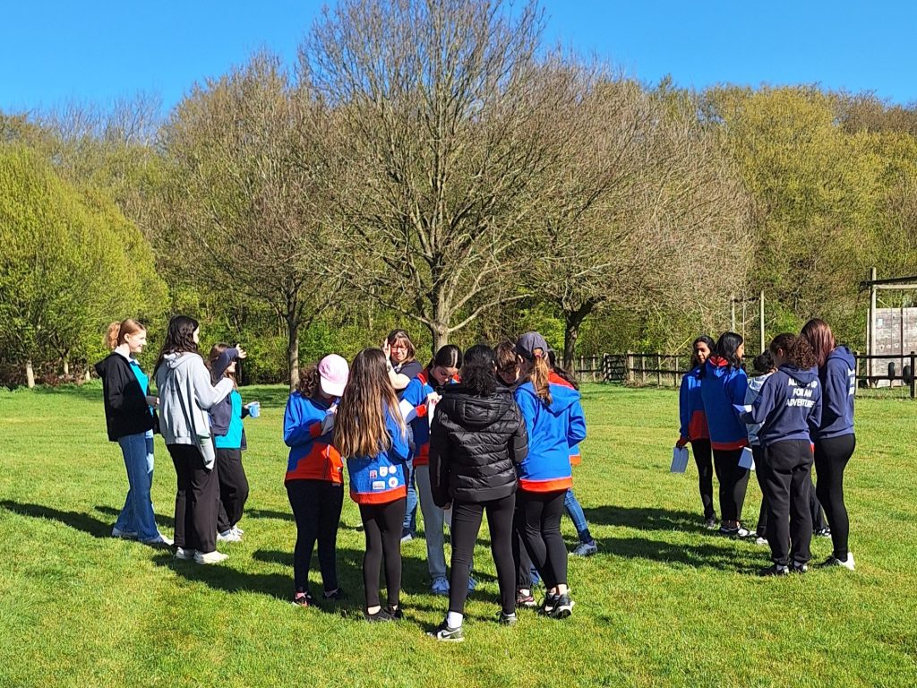 Guidesand Rangers gathered together outside on a sunny day in front of some trees.
