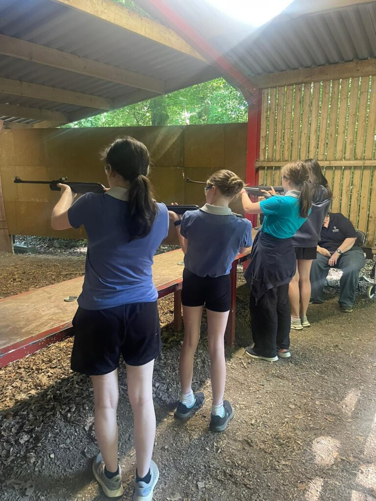 A row of girls with rifles in a rifle range.